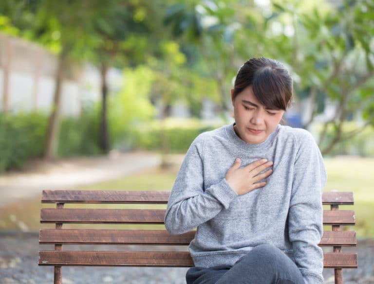 woman with her hand over her chest suffering from acid reflux  