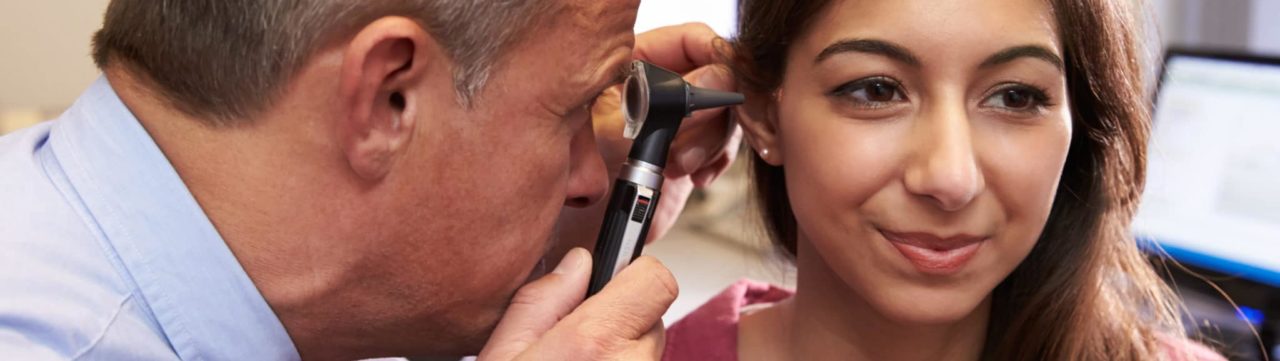 Doctor inspecting woman's ear with otoscope