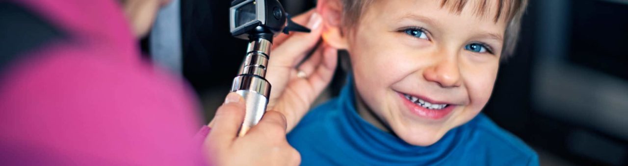 Doctor inspecting boys ear with otoscope