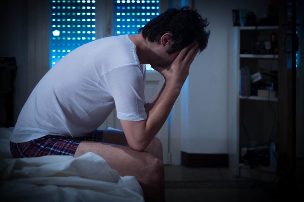 Man sitting up in bed unable to sleep