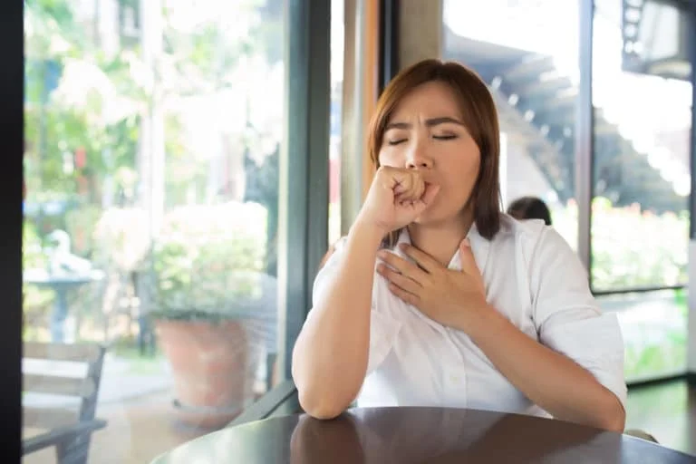 woman coughing into her hand