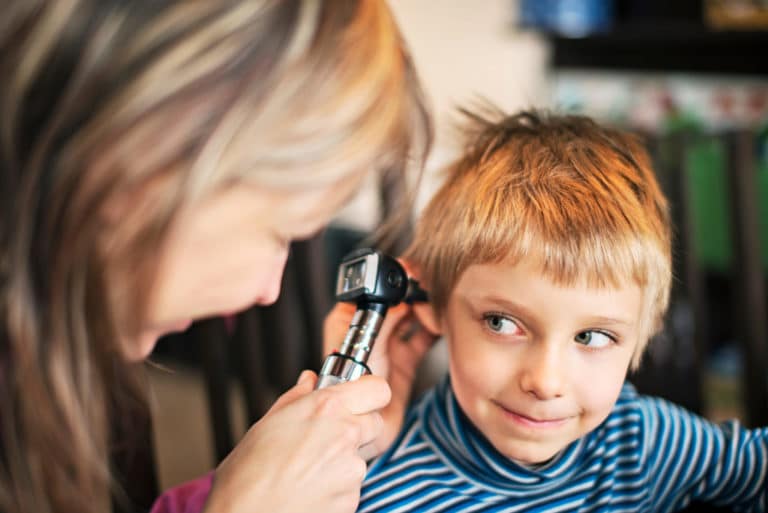 Doctor inspecting child's ear with otoscope